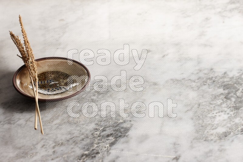 Wheat stalks on decorative pottery plate on grey marble background
