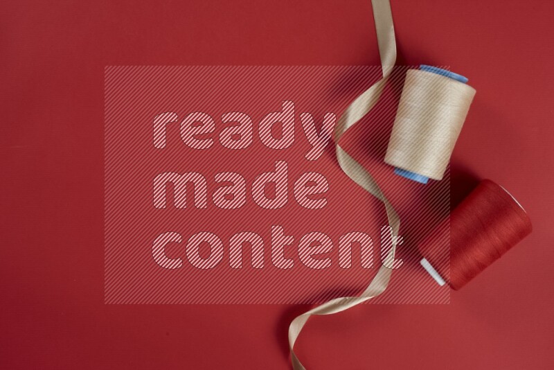 مجموعة من أدوات الخياطة والتفصيل بنية وحمراء اللون على خلفية حمراء