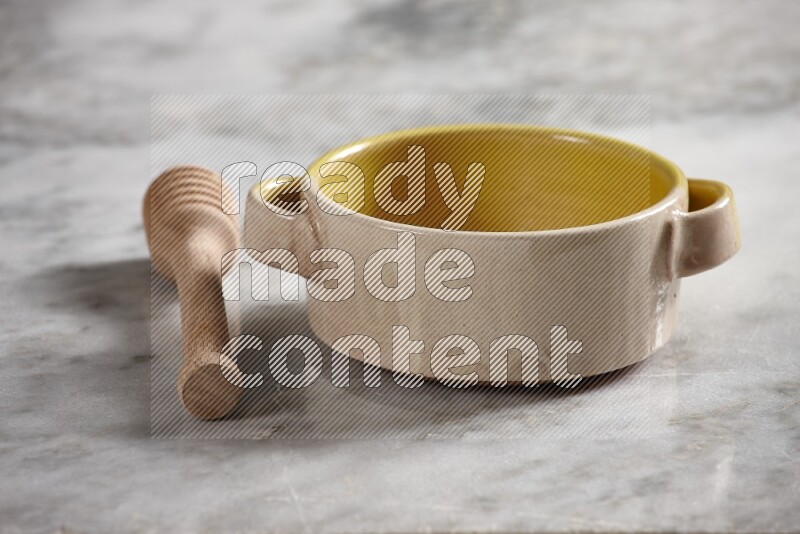 Multicolored pottery bowl with wooden honey dipper on the side on grey marble background
