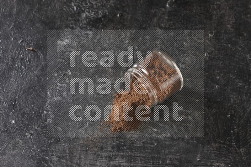 وعاء زجاجي مقلوب ممتلئ ببودرة القرنفل على أرضية سوداء