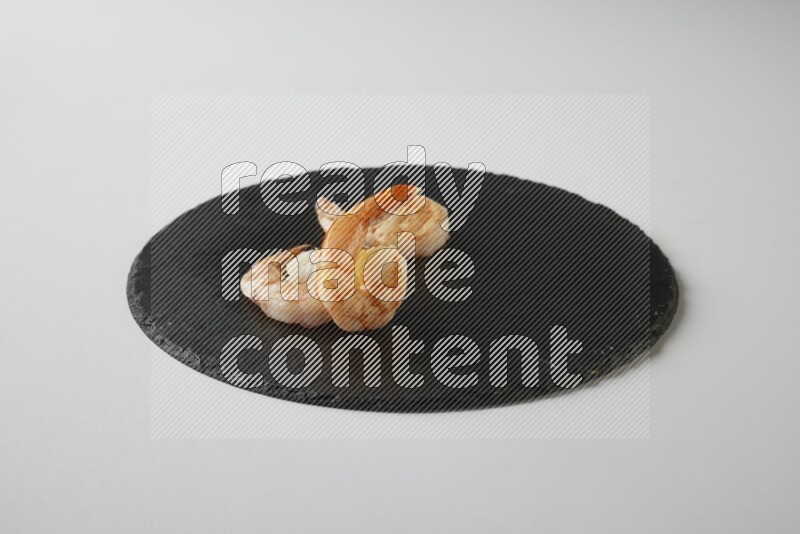 three grilled shrimp  on a black slate direct  on a white back ground