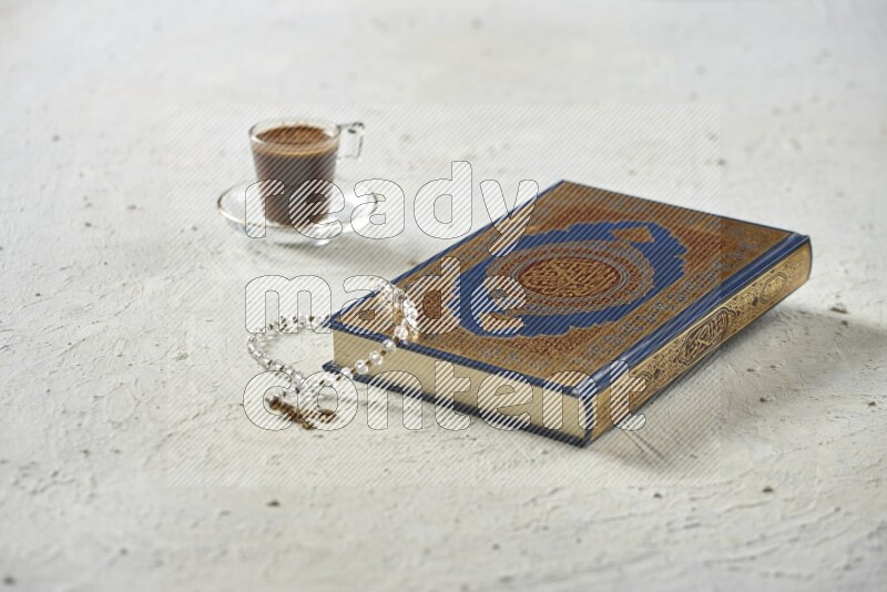 Quran with dates, prayer beads and different drinks all placed on textured white background