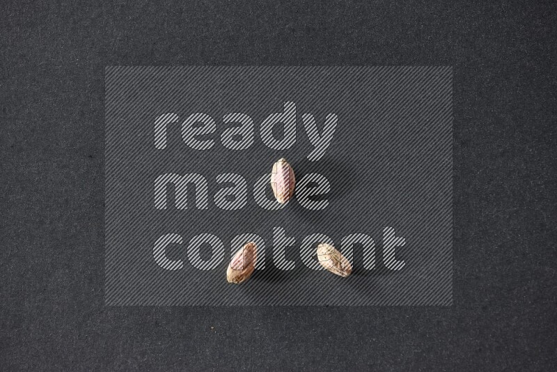 3 peeled pistachios on a black background in different angles