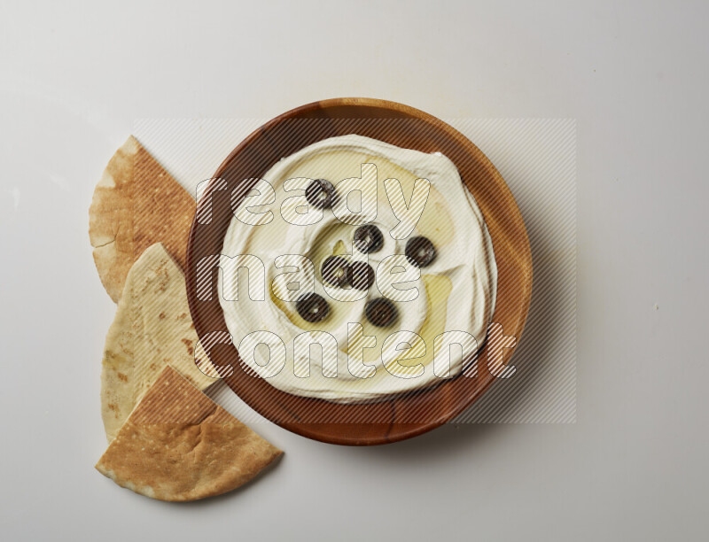 Lebnah garnished with sliced olives in a wooden plate on a white background