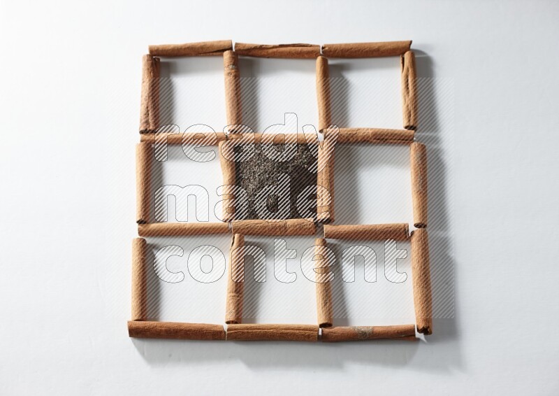 9 squares of cinnamon sticks full of tea in the middle surrounded by nutmeg, dried mint, cloves, dried basil, dried ginger, cinnamon, star anise and cardamom on white flooring