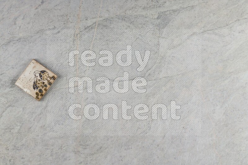 A decorative pottery coaster on grey marble background