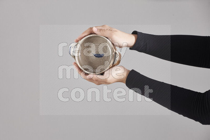 A woman in black abaya holding different pottery essentials in different positions