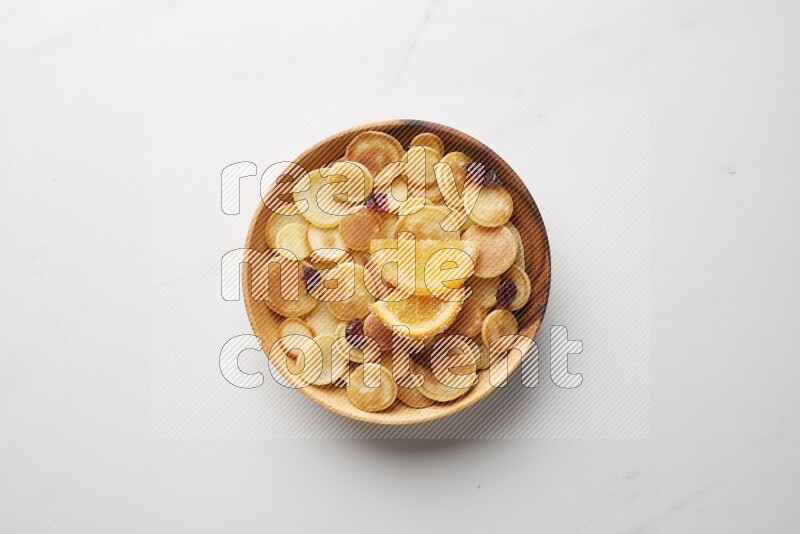 Top-view shot of orange candy cereal pancakes in a round bowl on white background