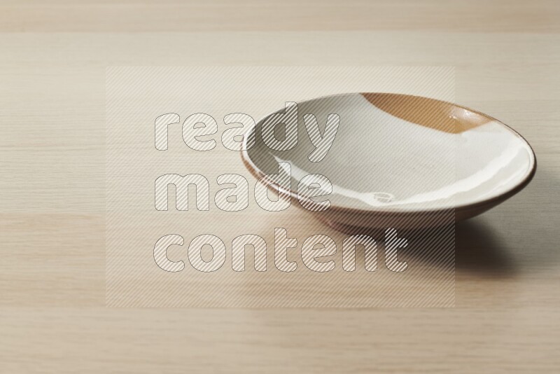 A multicolored pottery plate on light wooden background