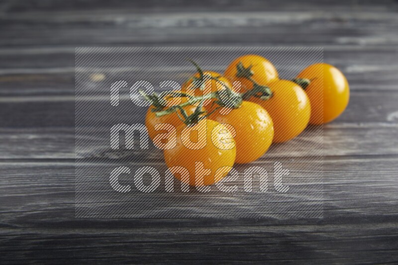 Yellow cherry tomato vein on a textured grey wooden background 45 degree