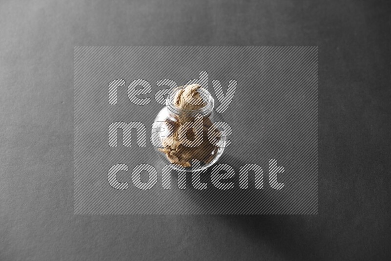 A glass spice jar full of ginger on black flooring