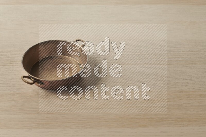 A small copper pan on light wooden background