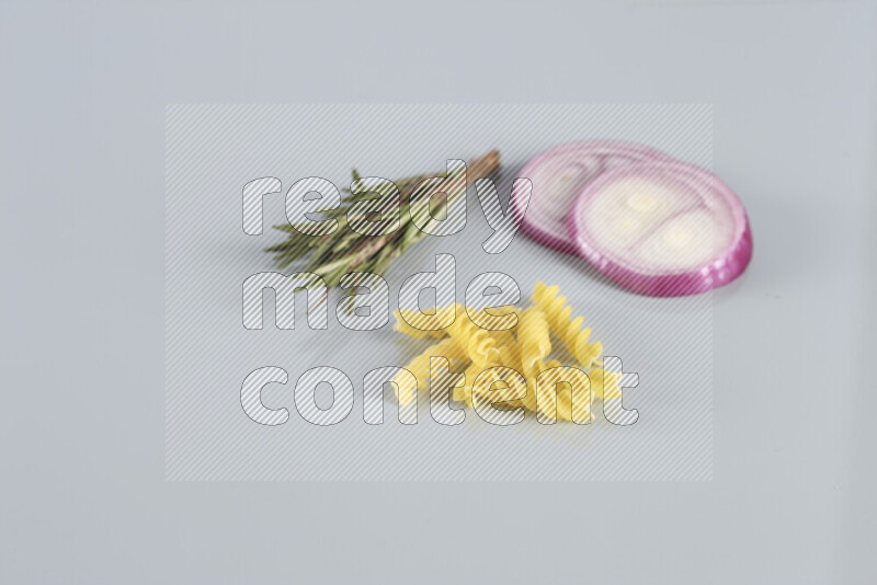 Raw pasta with different ingredients such as cherry tomatoes, garlic, onions, red chilis, black pepper, white pepper, bay laurel leaves, rosemary, cardamom and mushrooms on light blue background