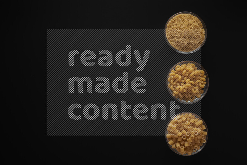Different pasta types in 3 glass bowls on black background