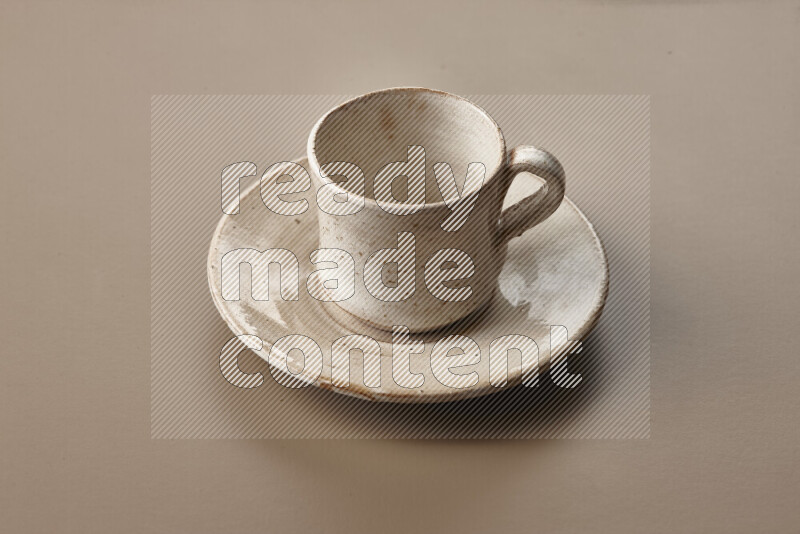 A beige pottery cup full of roasted coffee beans on beige background