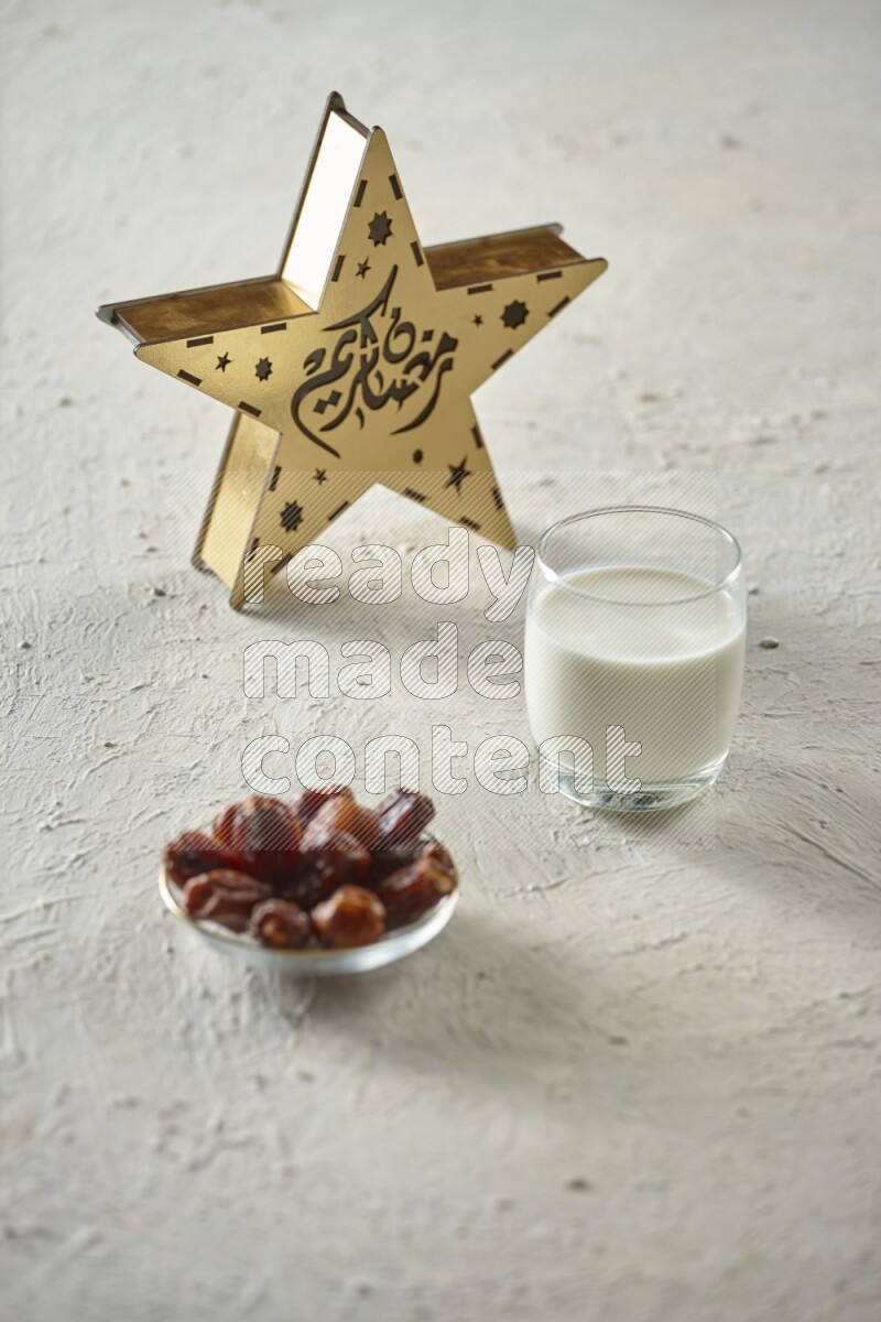 A wooden golden star lantern with different drinks, dates, nuts, prayer beads and quran on textured white background