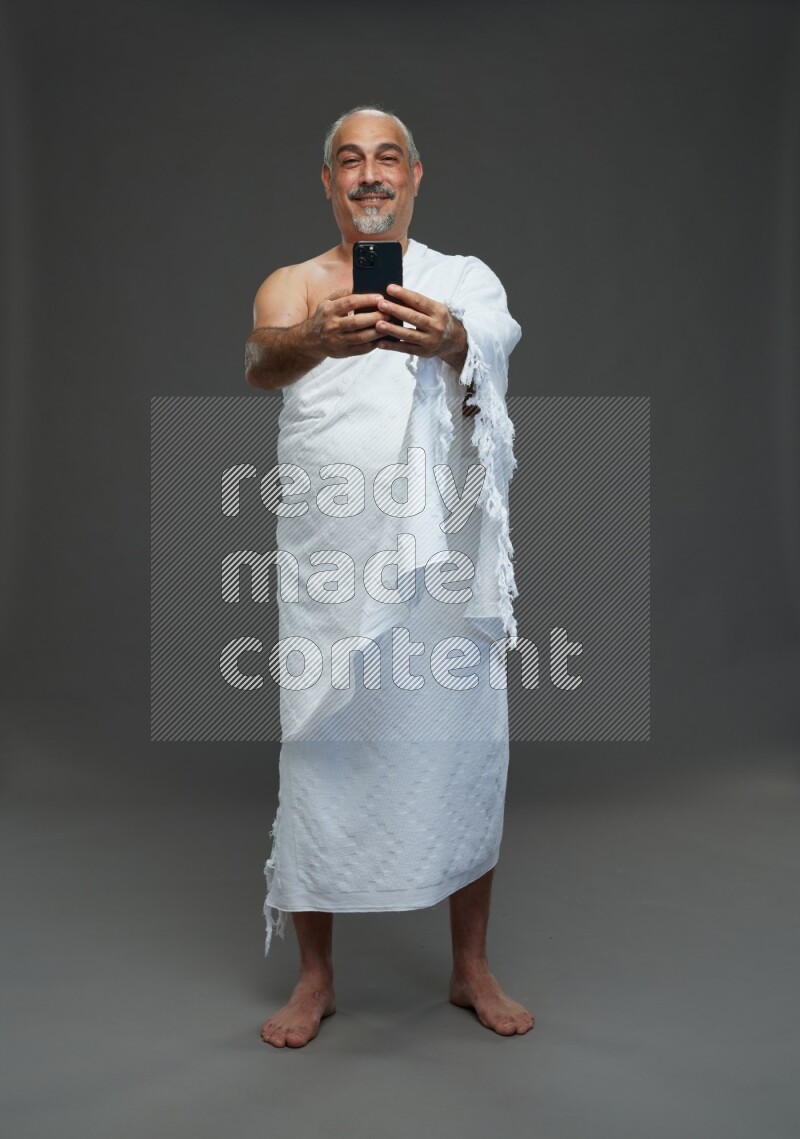 A man wearing Ehram Standing taking selfie on gray background