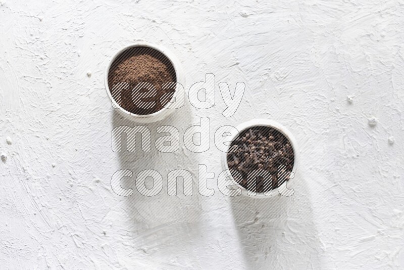 وعاءين من السيراميك بيج اللون، أحدهما مملوء بالقرنفل والآخر مملوء بالبودرة على أرضية بيضاء