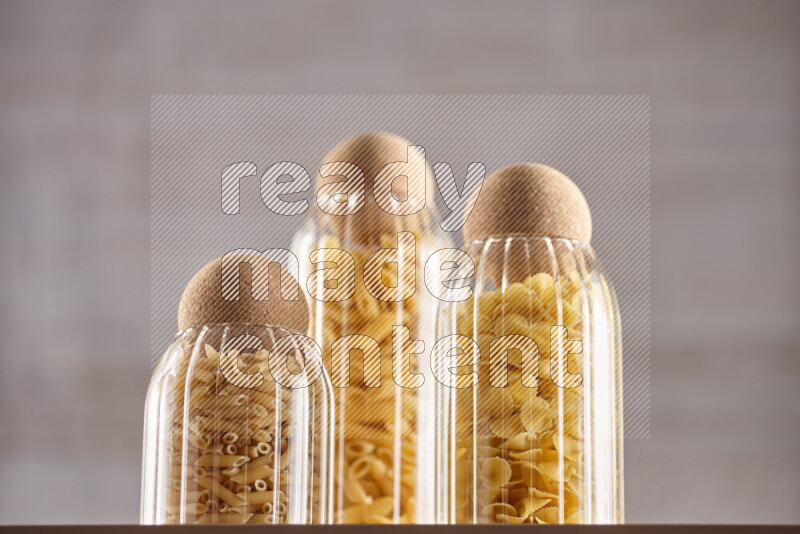 Raw pasta in glass jars on beige background