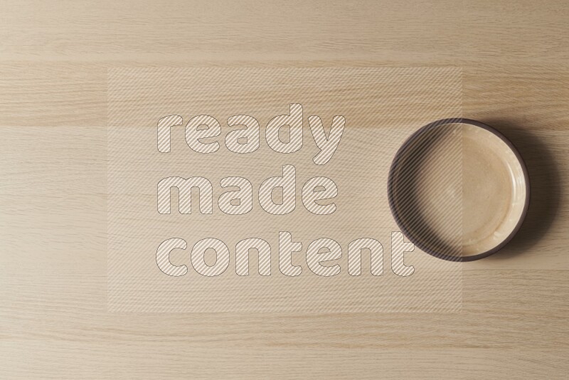 A beige pottery oven bowl on light wooden background