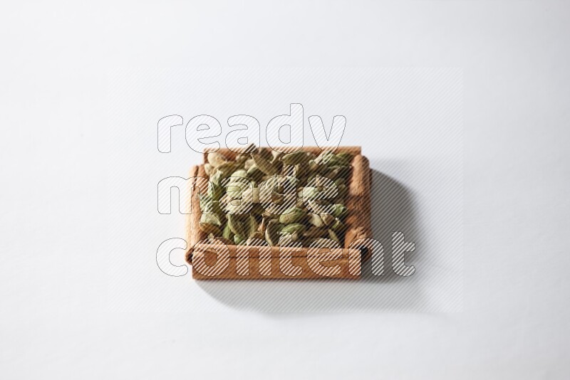 أربعة من أعواد القرفة مكونة شكل مربع بداخلها حبوب الهيل علي خلفية بيضاء