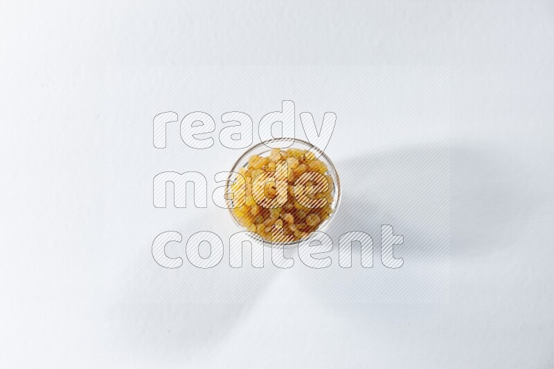 A glass bowl full of raisins on a white background in different angles