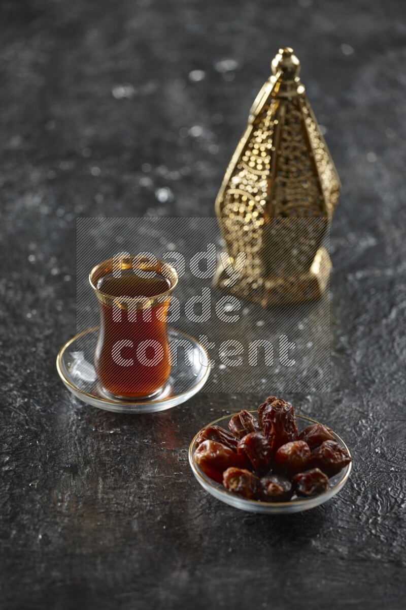 A golden lantern with different drinks, dates, nuts, prayer beads and quran on textured black background