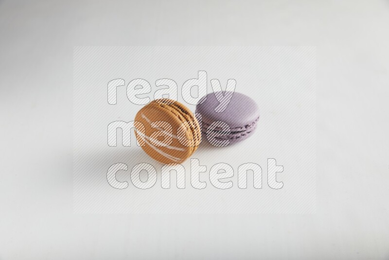 45º Shot of of two assorted Brown Irish Cream, and Purple Blueberry macarons on white background