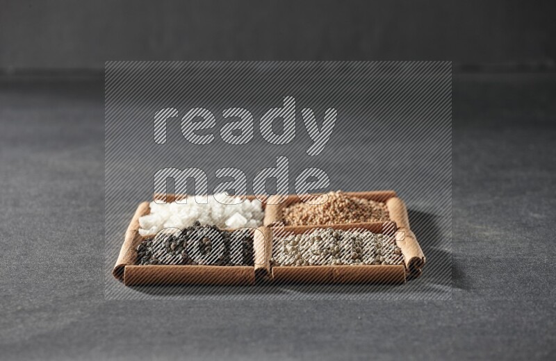4 squares of cinnamon sticks full of black pepper, white pepper, white salt and mustard seeds on black flooring