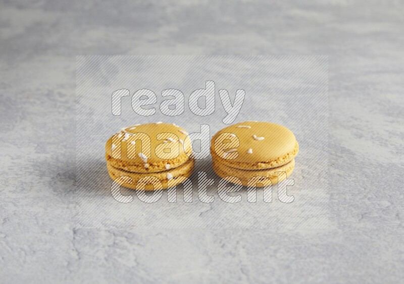 45º Shot of two Yellow Piña Colada macarons  on white  marble background
