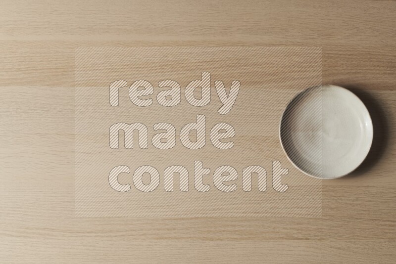 A beige pottery plate on light wooden background