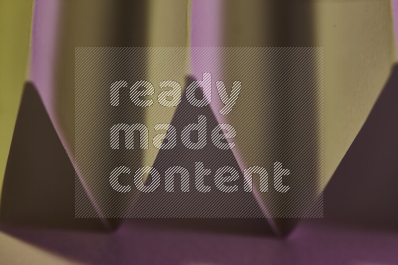 A close-up abstract image showing sharp geometric paper folds in pink gradients and warm tones