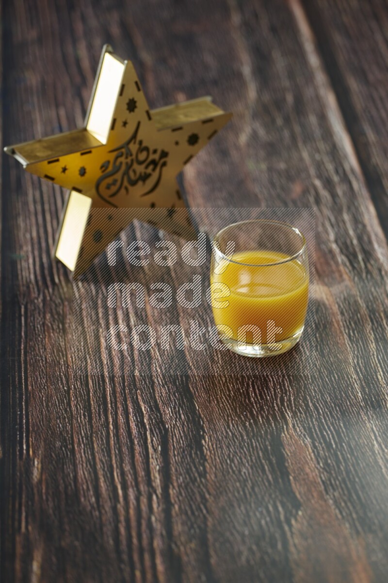 A wooden golden star lantern with different drinks, dates, nuts, prayer beads and quran on brown wooden background