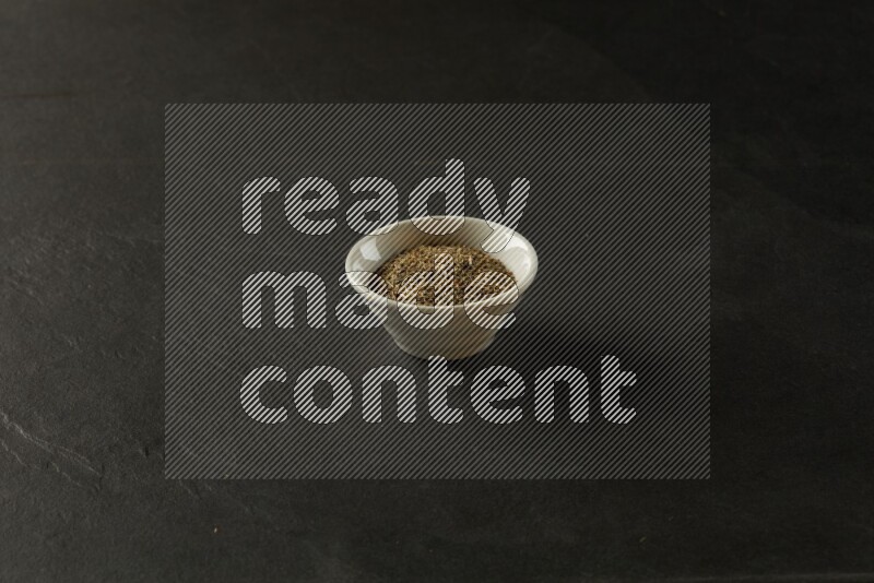 white ceramic round sauce bowl filled with herbs on grey textured countertop