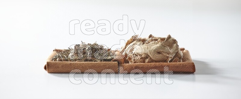 2 squares of cinnamon sticks full of dried ginger and dried basil on white flooring