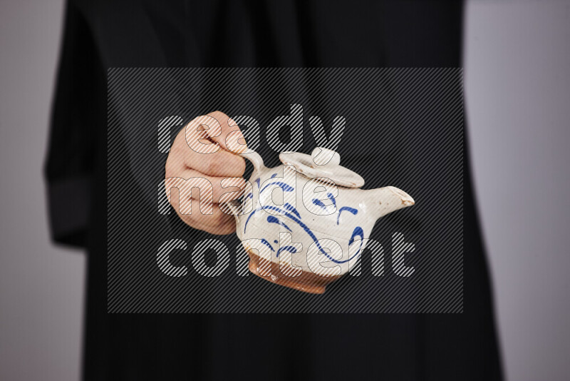 A woman in black abaya holding different pottery essentials in different positions