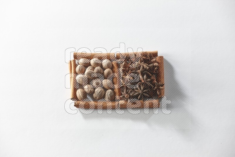 مربعان من أعواد القرفة ممتلئان باليانسون النجمي وجوزة الطيب علي خلفية بيضاء