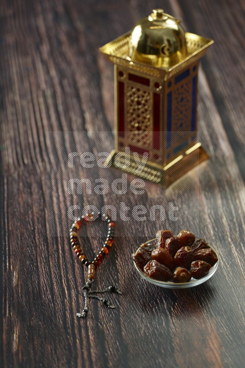 A golden lantern with different drinks, dates, nuts, prayer beads and quran on brown wooden background