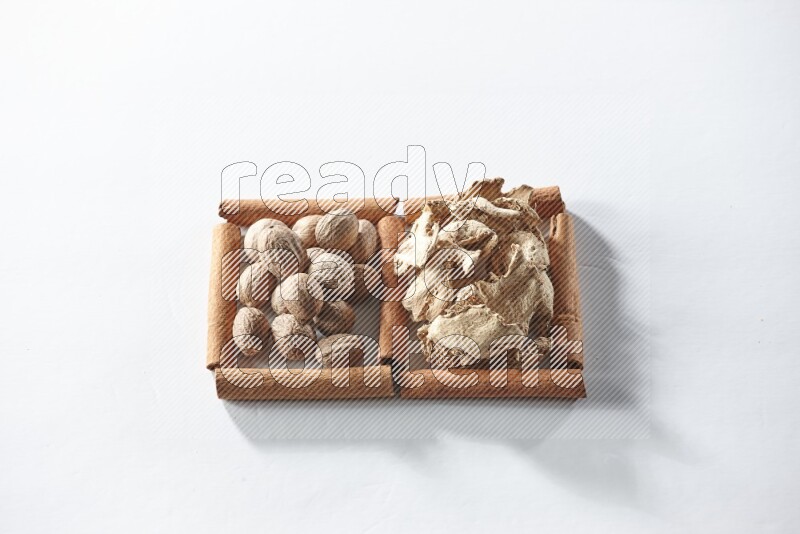 2 squares of cinnamon sticks full of dried ginger and nutmegs on white flooring
