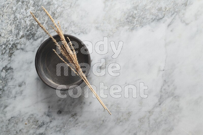 Wheat stalks on black pottery oven plate on grey marble background
