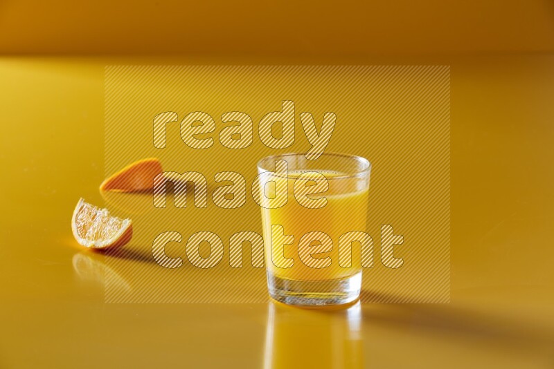 glass of orange juice on yellow background