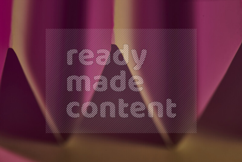 صورة مجردة مقربة تظهر طيات ورقية هندسية حادة بتدرجات اللون الوردي مع درجات لونية دافئة