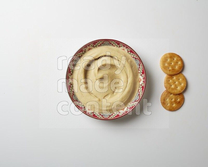 Plain Hummus in a red plate with patterns on a white background