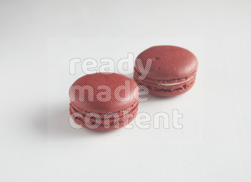 45º Shot of two Red Velvet macarons on white background