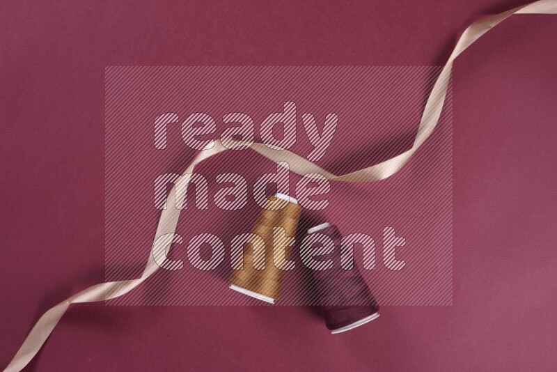 مجموعة من أدوات الخياطة والتفصيل بنية وحمراء اللون على خلفية حمراء