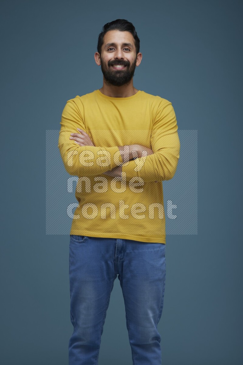 Man posing in a blue background wearing a yellow shirt