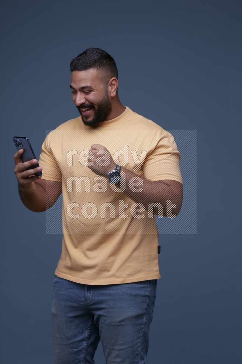 A man Texting on his phone on Blue Background wearing Orange T-shirt