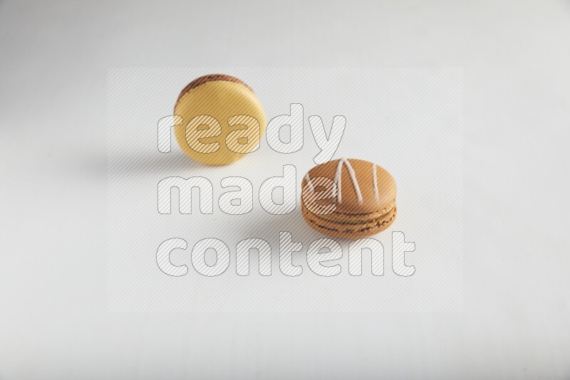 45º Shot of of two assorted Brown Irish Cream, and Yellow, and Brown Chai Latte macarons on white background