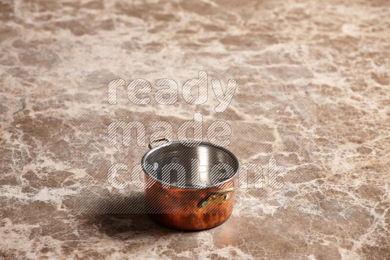 A small copper pot on beige marble background