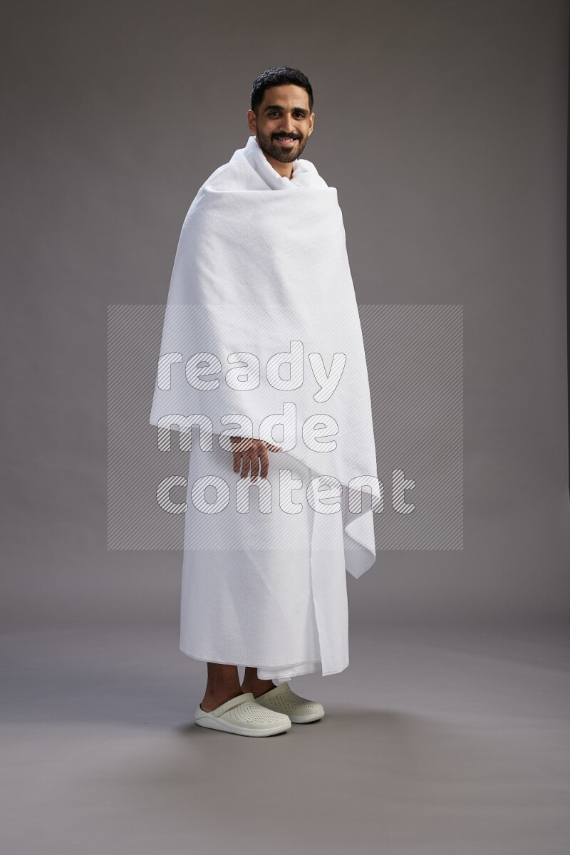 A man wearing Ehram Standing Interacting with the camera on gray background